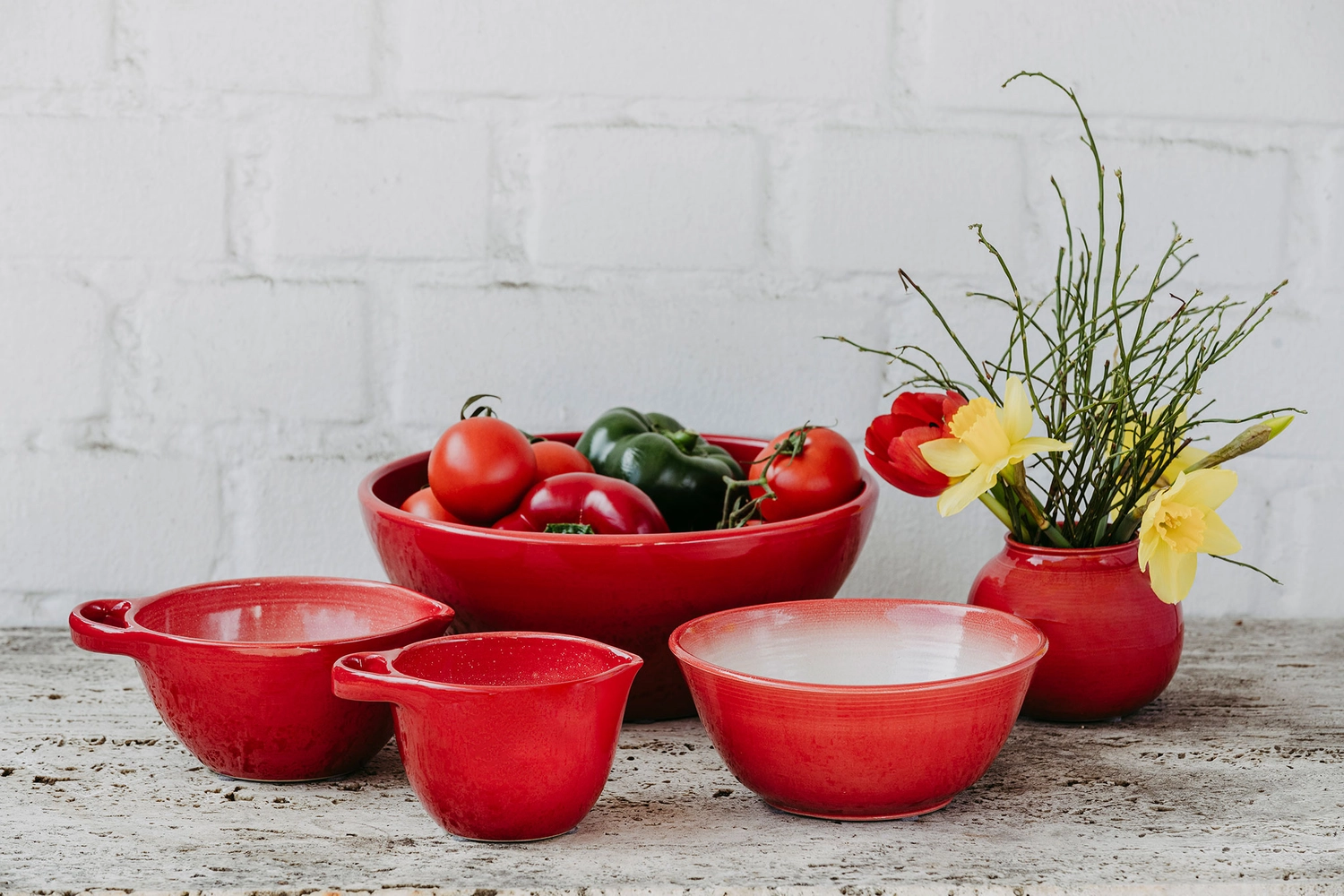 Keramik Atelier Melis - Töpferkurse - Töpferkurse, bei denen rote Keramikschalen und eine Vase mit Blumen gezeigt werden.