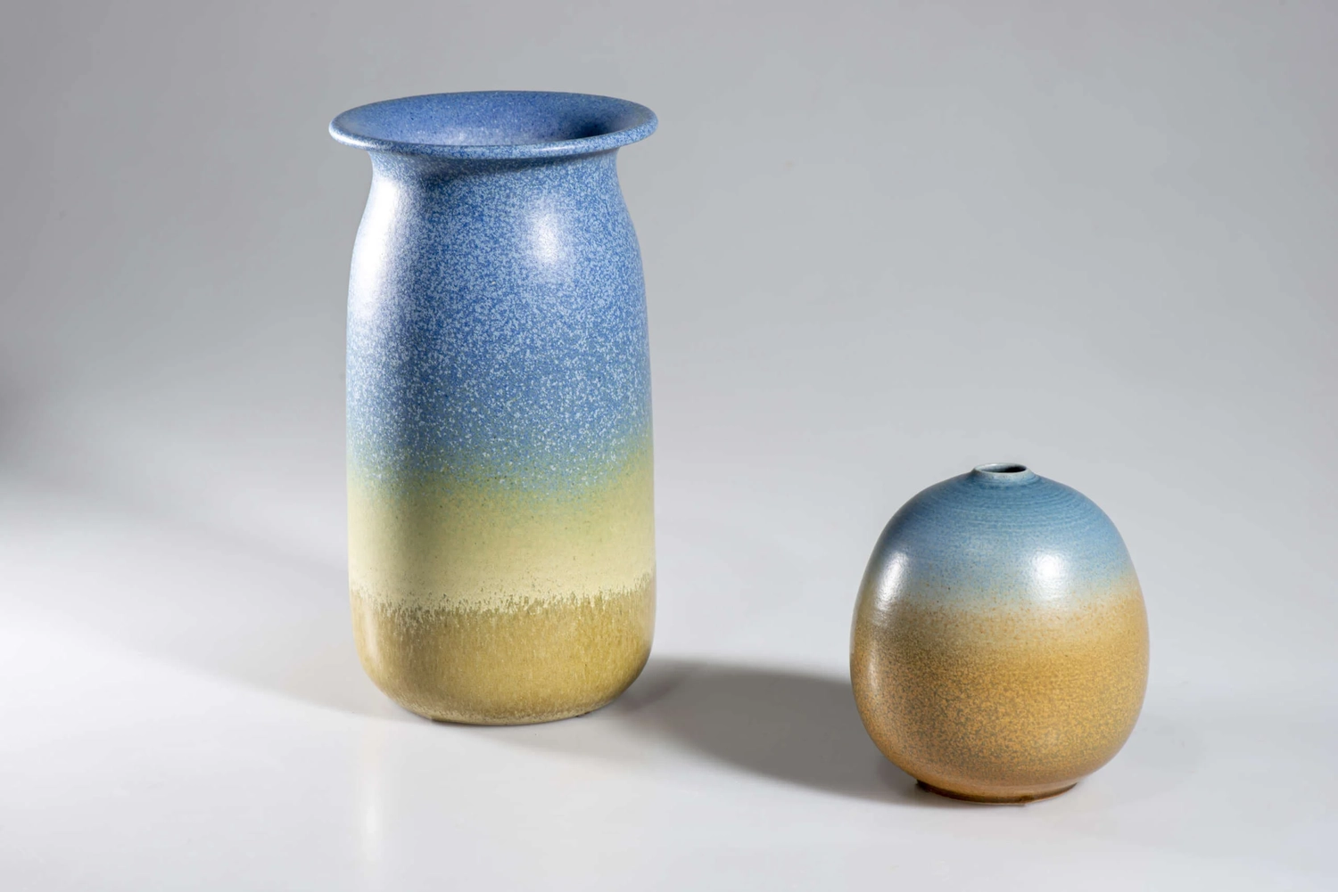 Keramik Atelier Melis - Töpferkurse - Zwei Keramikvasen, eine hohe und eine niedrige, mit einer blau-gelb verlaufenden Glasur.