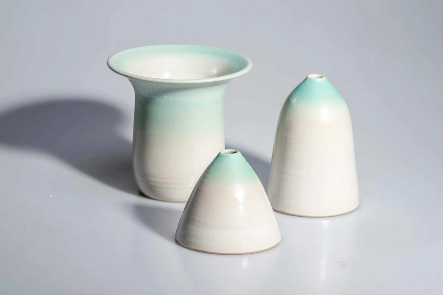 Keramik Atelier Melis - Töpferkurse - Drei Keramikvasen in verschiedenen Größen mit einer Glasur, die von Weiß zu Hellgrün verläuft.