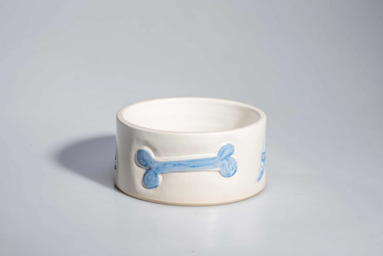 Keramik Atelier Melis - Töpferkurse - Ein weißer Keramik-Hundenapf mit blauem Knochenmuster.