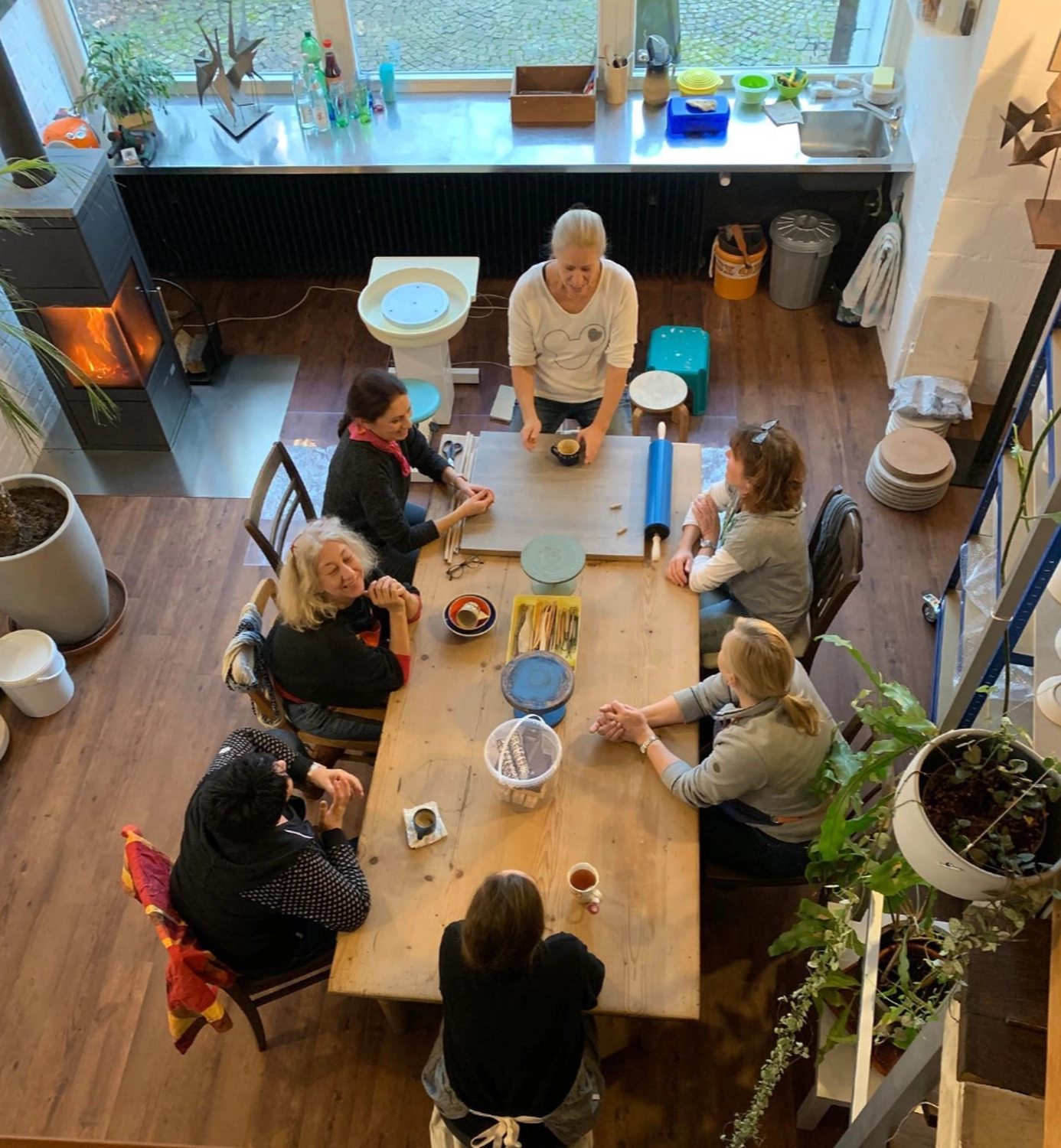 Keramik Atelier Melis - Töpferkurse - Eine Gruppe von sechs Frauen sitzt um einen Holztisch in einem Töpferatelier.