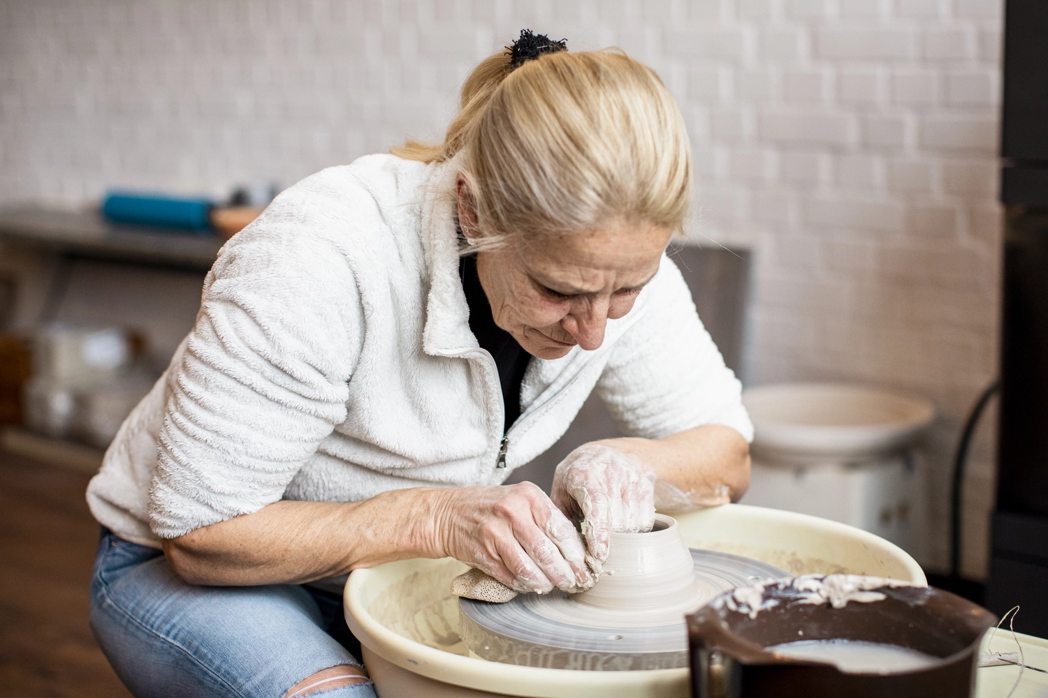Keramik Atelier Melis - Töpferkurse - Eine Frau formt einen Tontopf auf einer Töpferscheibe.