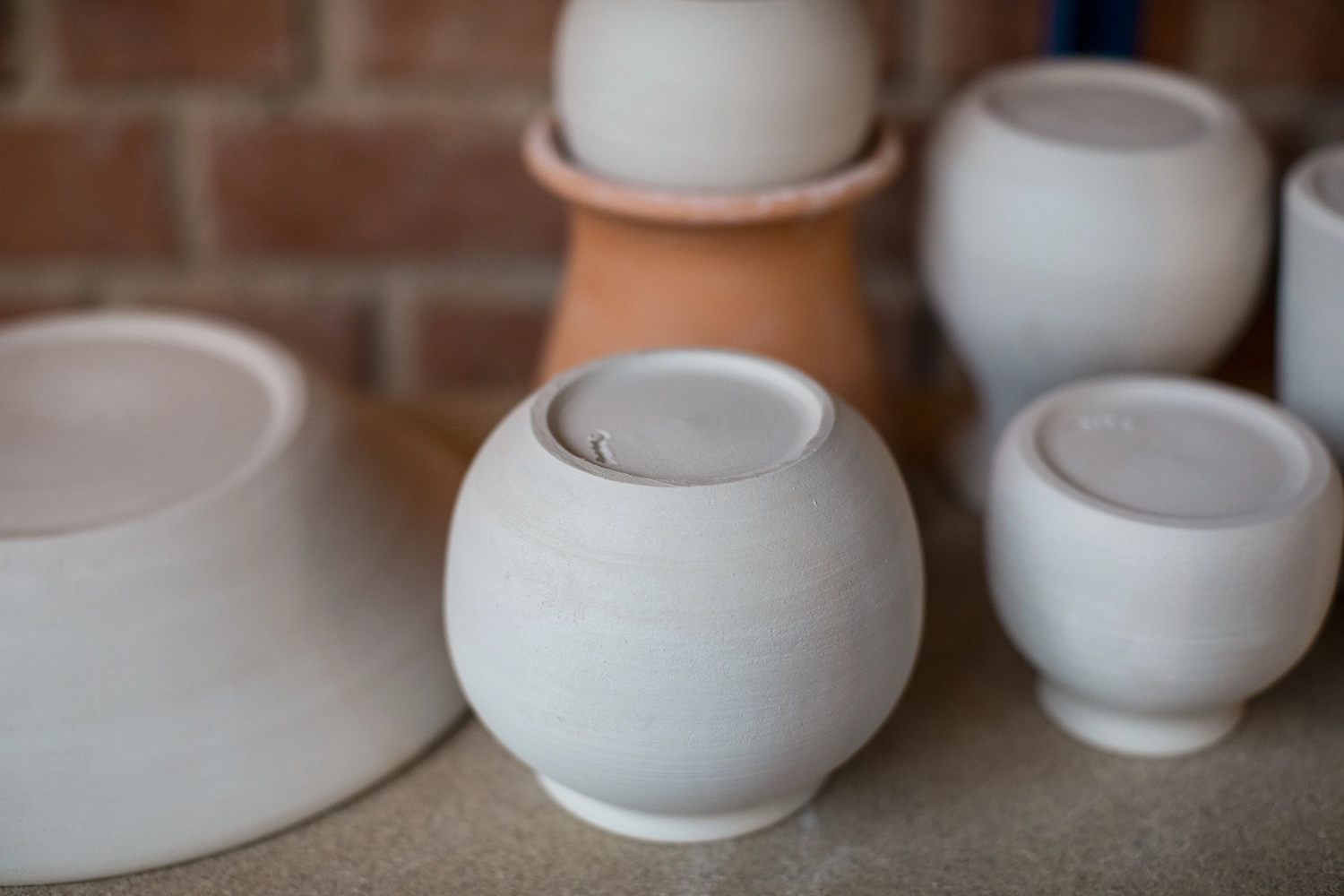 Keramik Atelier Melis - Töpferkurse - Es handelt sich um unglasierte Keramik- oder Betongefäße, wahrscheinlich Vasen oder Pflanzgefäße, in verschiedenen kugelförmigen oder schalenförmigen Ausführungen.